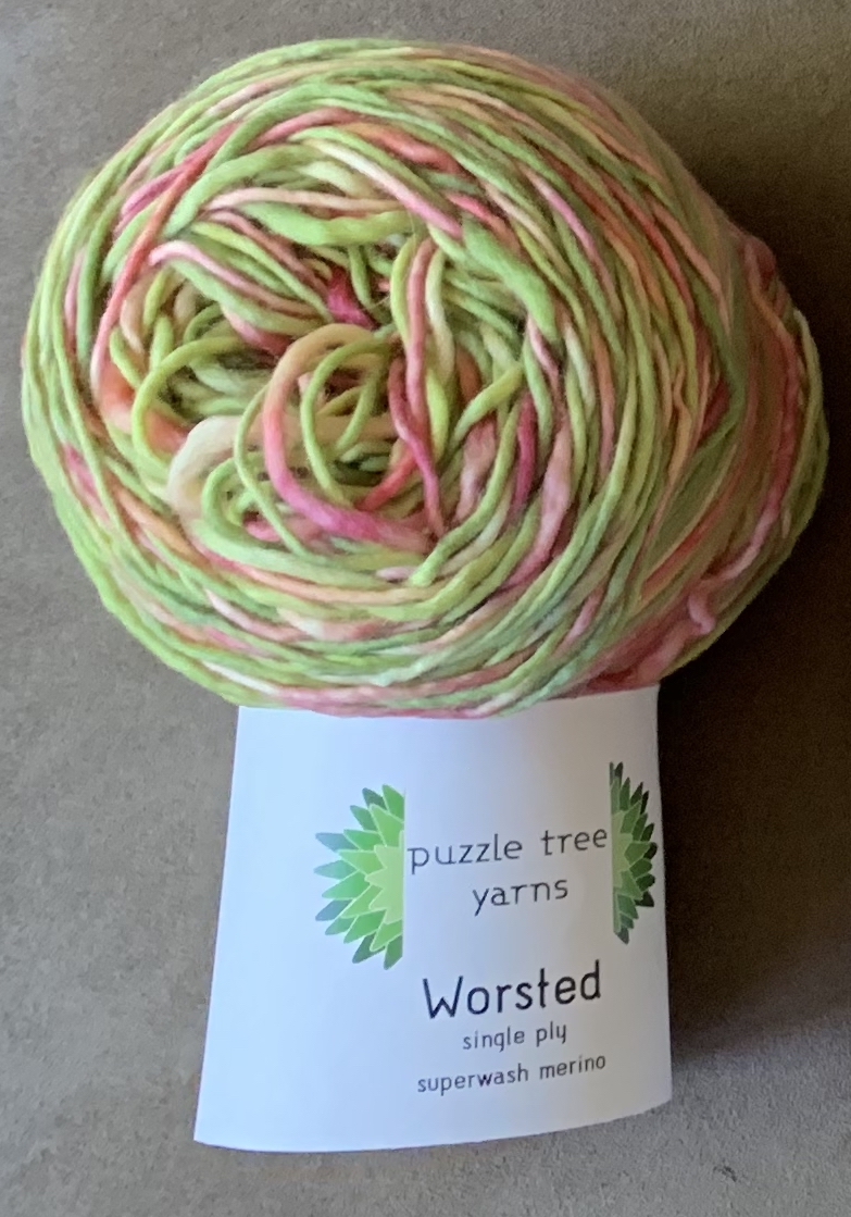 Greens and pinks in a worsted-weight, single ply, merino yarn and a puzzle tree yarns label.