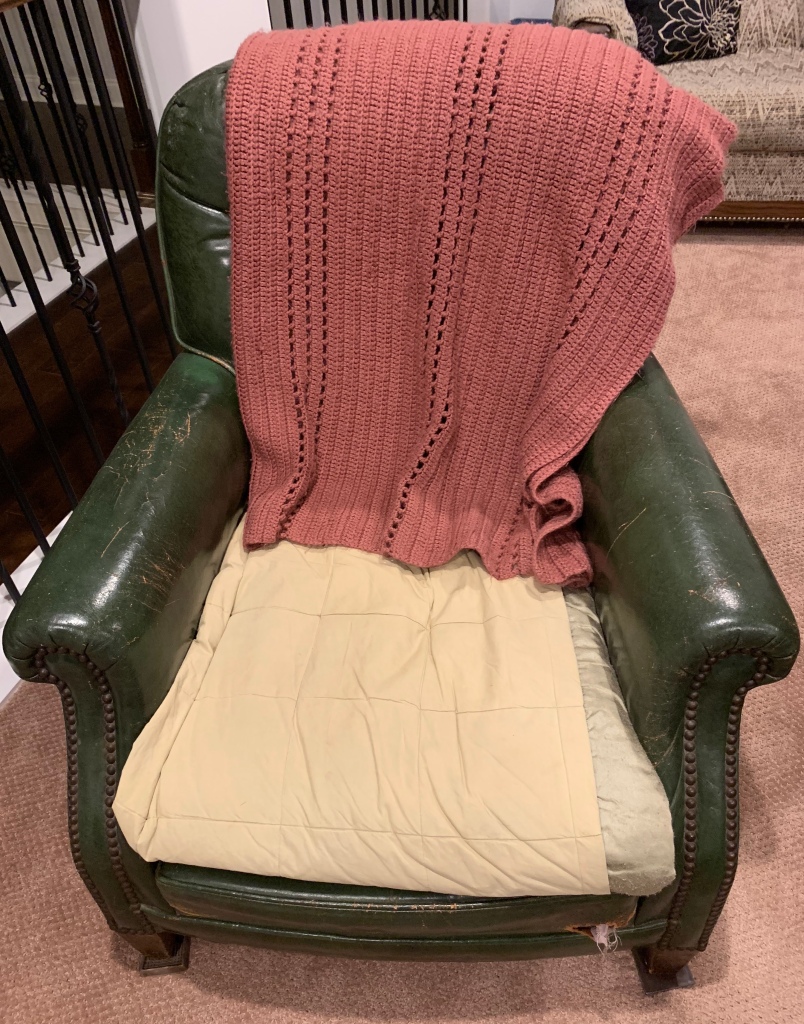 pink crocheted blanket on a green leather chair